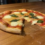 Close-up of baked discarded sourdough pizza dough with golden crust and melted cheese