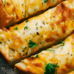 A golden-brown loaf of garlic bread with melted cheese, fresh out of the oven.
