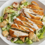 A vibrant bowl of Caesar Slaw with Crunchy Chicken, garnished with fresh herbs.