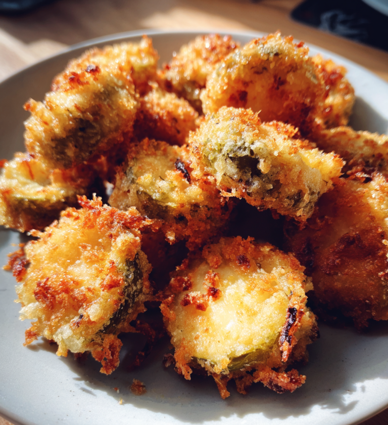 Golden-brown crispy pickle cheese bites piled on a plate as a quick snack.
