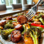 Sheet pan honey garlic kielbasa and roasted vegetables including broccoli and bell peppers.