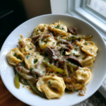 Philly cheesesteak tortellini pasta with steak, green peppers, and melted cheese in a bowl.