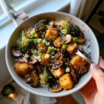 Crispy tofu and mushroom stir-fry with broccoli and sesame seeds over white rice.