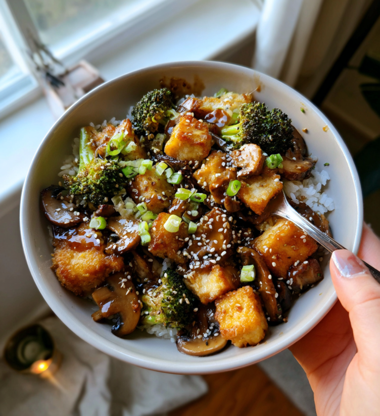 Crispy tofu and mushroom stir-fry with broccoli and sesame seeds over white rice.